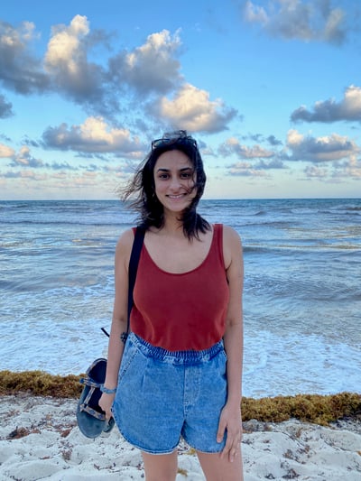 Shobhana smiling on the beach with a breeze through her hair, blue skies and blue waters