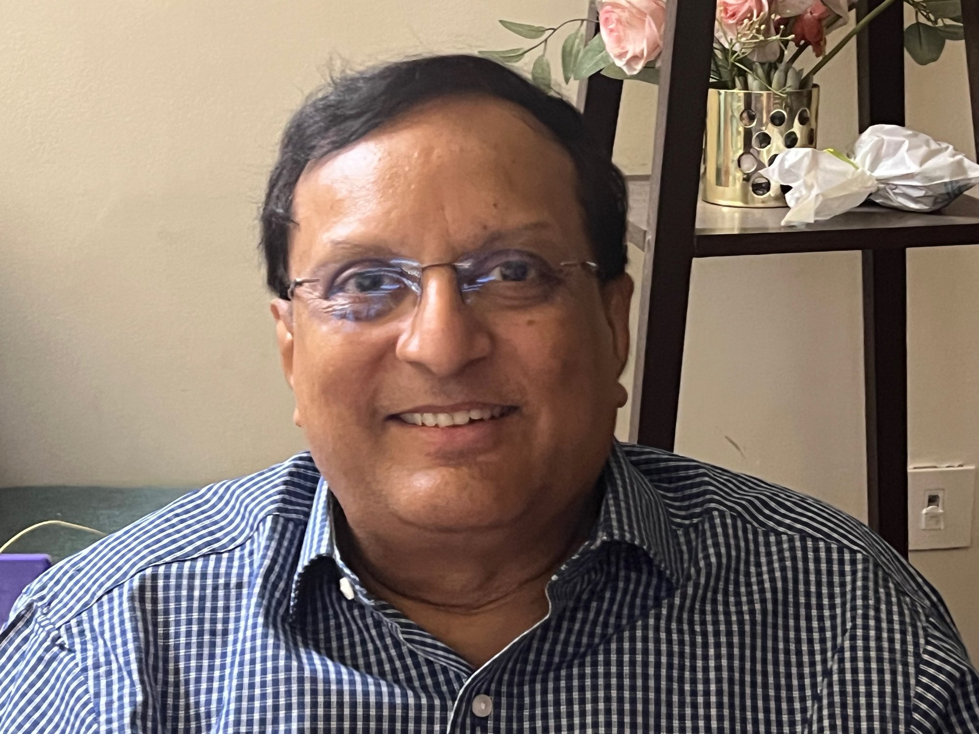 Raghu in a blue checkered shirt, smiling.